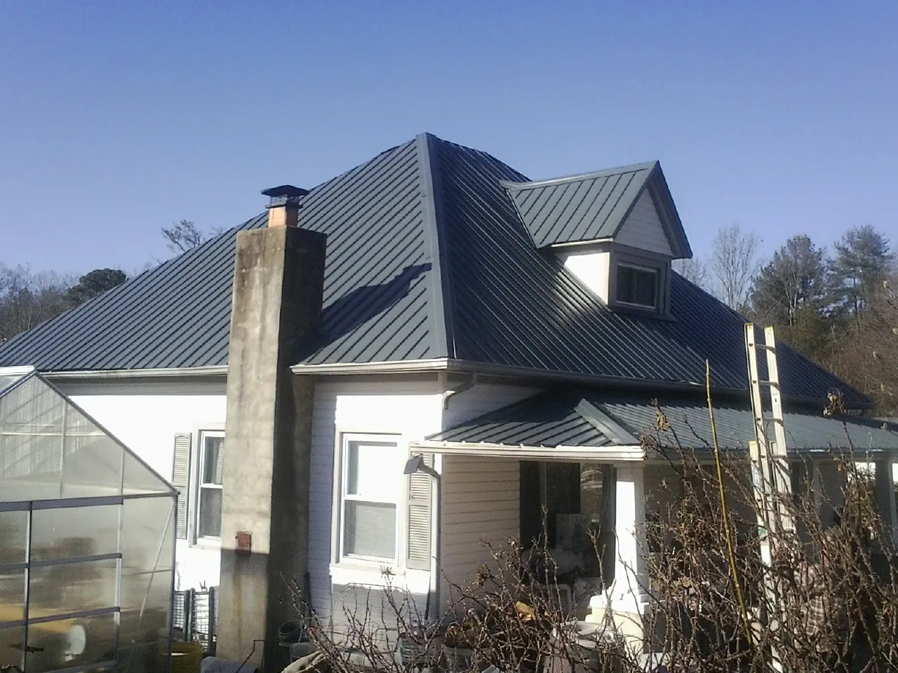 Dark blue standing seam metal roof on a white farmhouse with dormer — Slate & Tile Roof Repair by Roofing Brothers in Pottsboro
