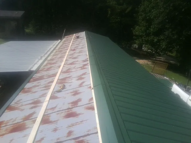 Old rusted panels beside newly installed green metal roofing — Wind Damage Roof Repair by Roofing Brothers in Pottsboro