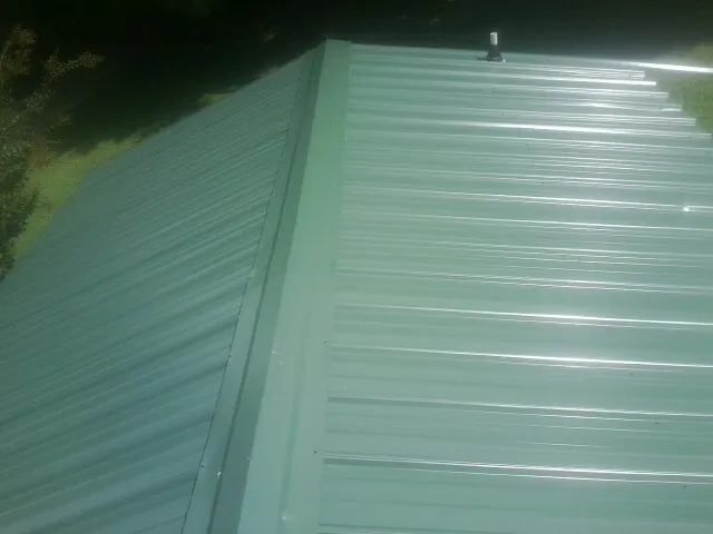 New green metal panels meeting at the ridge of a roof — Flat Roof Repair work by our crew in Pottsboro