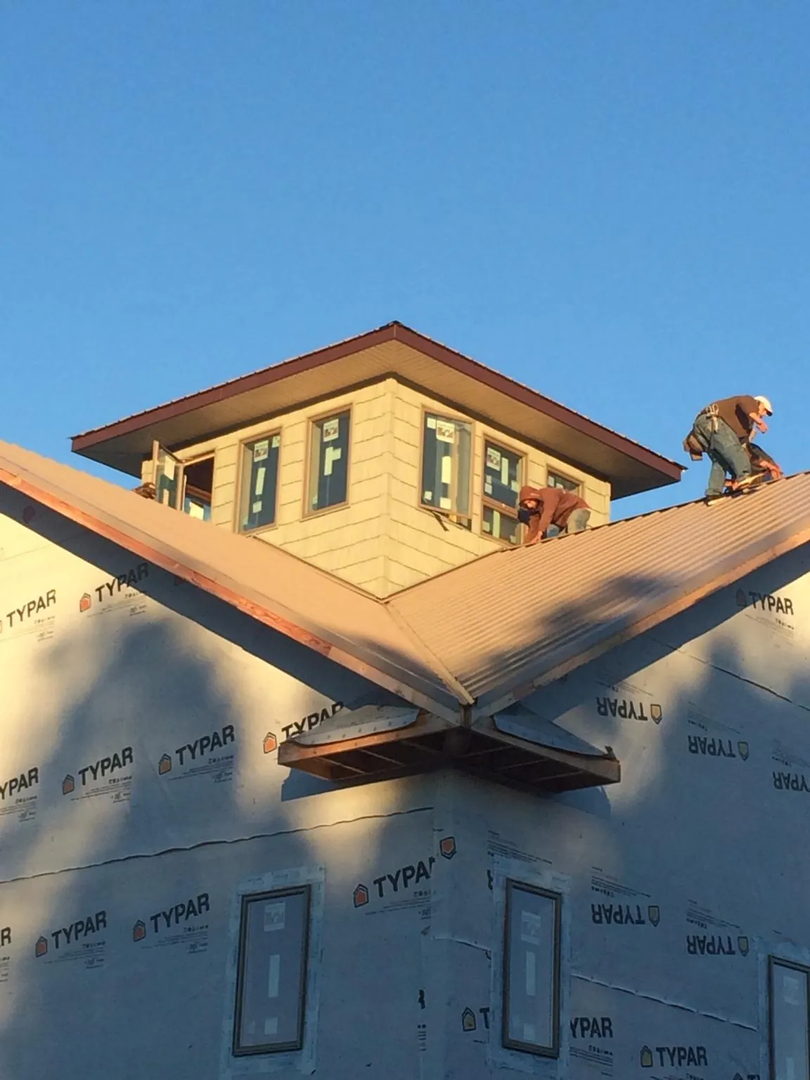 Roofers working around a rooftop cupola on a new metal roof at sunset — Roof Waterproofing in Pottsboro by Roofing Brothers